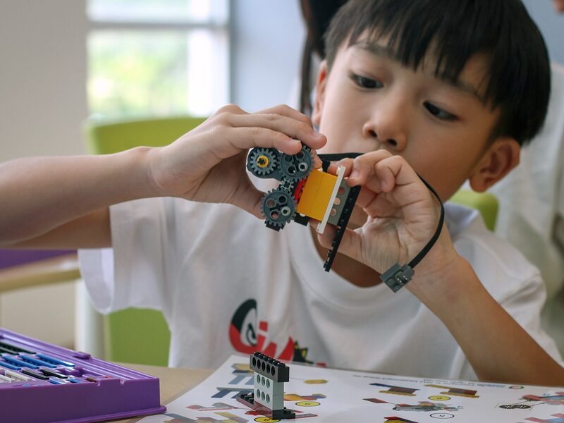 Boy building motorized mechanism with wires and gears